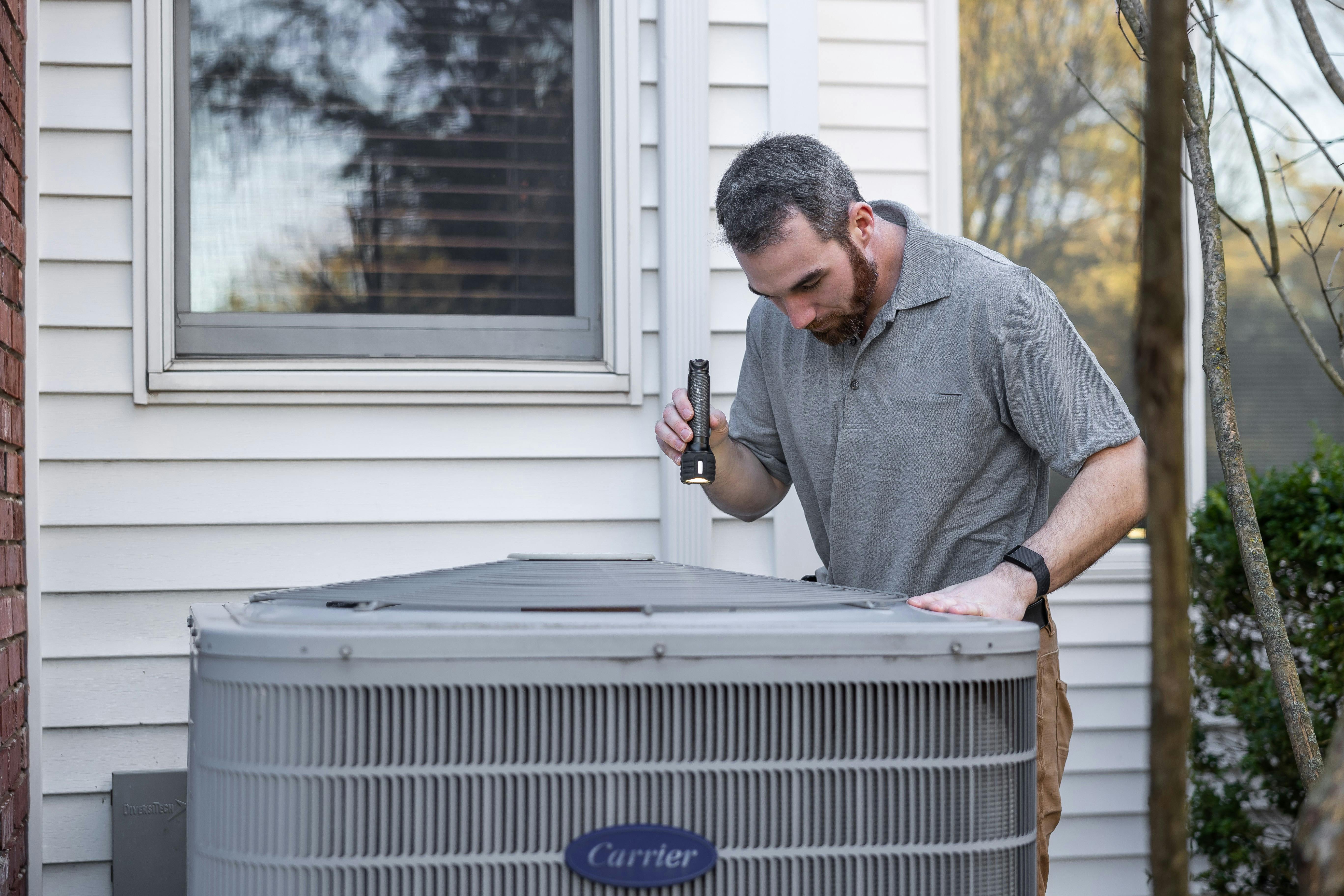 Professional HVAC technician servicing Carrier air conditioning unit in Fairbanks, Alaska